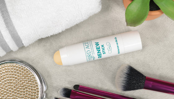 image of Third Age Renew Stick moisturizer on countertop next to towel, brush and plant