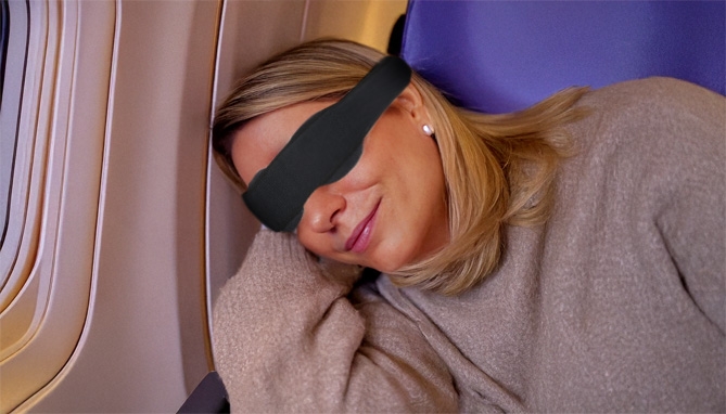 image of woman wearing black out mask; carry on luggage travel essential